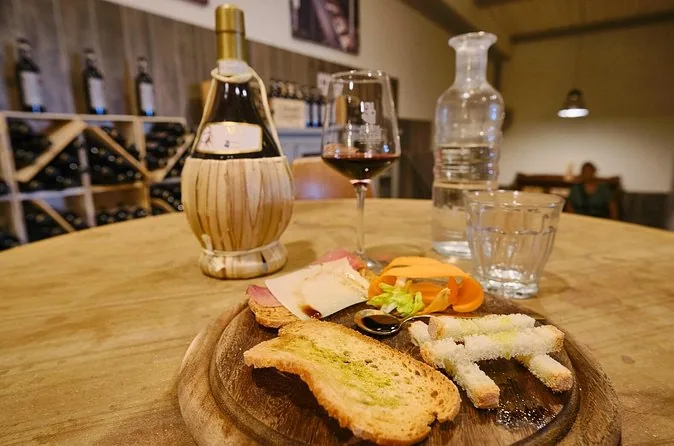 A straw-covered Chianti flask, a glass of red wine and bruschetta on a tasting table